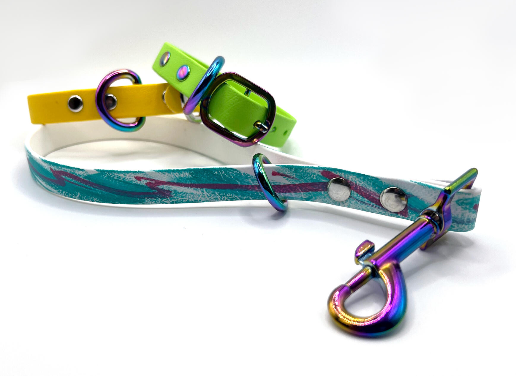 A biothane keychain with the 80s retro "Jazzy" design painted on it. It has a yellow collar and a green collar laying on it.